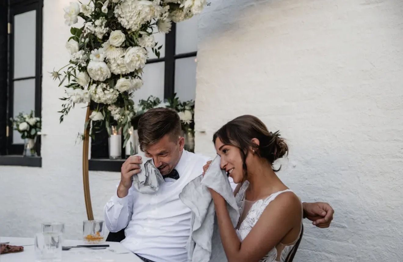 A couple laughing together at their reception table