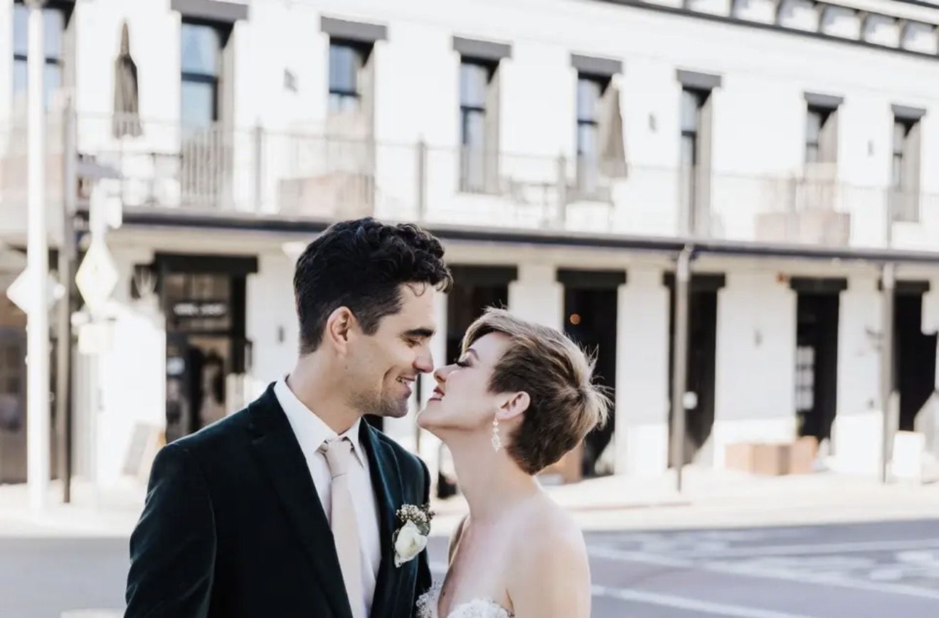A couple about to kiss on the street outside a historic hotel