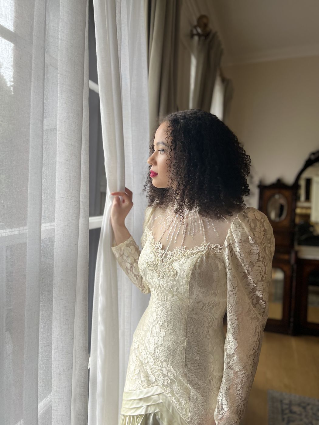 A bride at a window in a lace gown